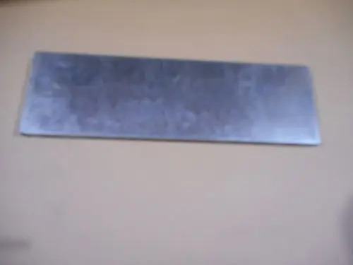 Ein grau-metallisches Plattenelement an einer Wand, das möglicherweise Teil eines Heiz- oder Befestigungssystems von Remeha ist.